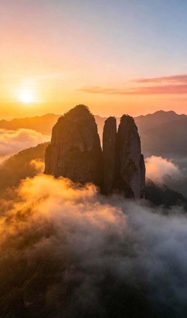 The three red Danxia peaks of Jianglang Shan rising above a sea of cloud at sunset.